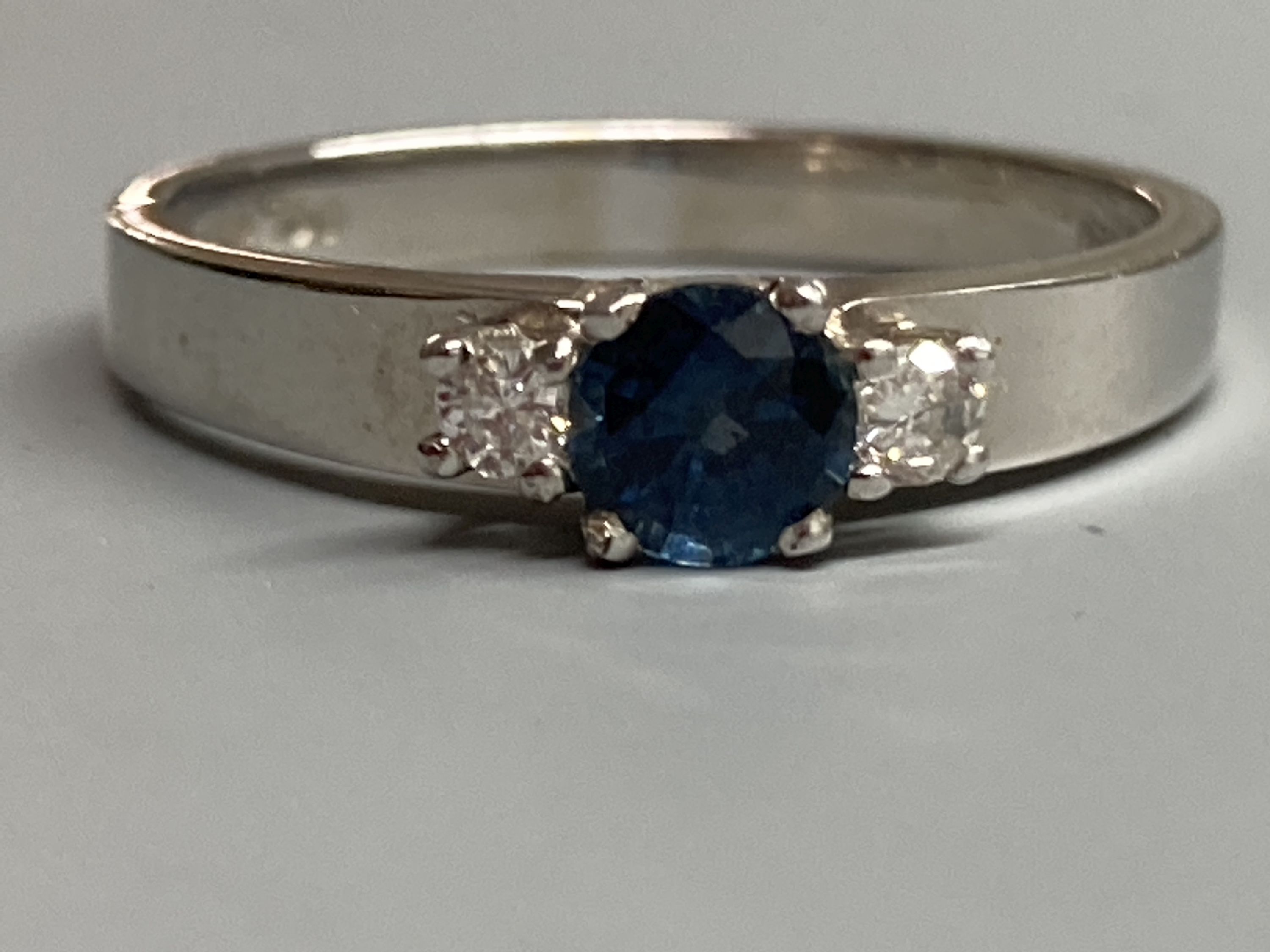 A modern 18ct white gold, sapphire and diamond set three stone ring, size N/O, gross 3.2 grams.